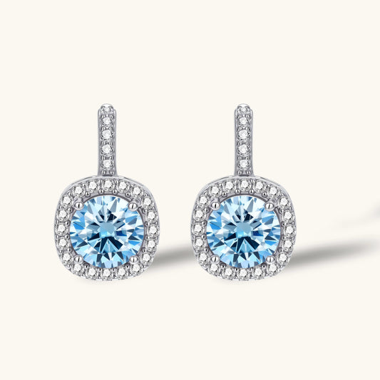 Sterling silver drop earrings featuring cushion-cut blue moissanite stones surrounded by sparkling halo settings