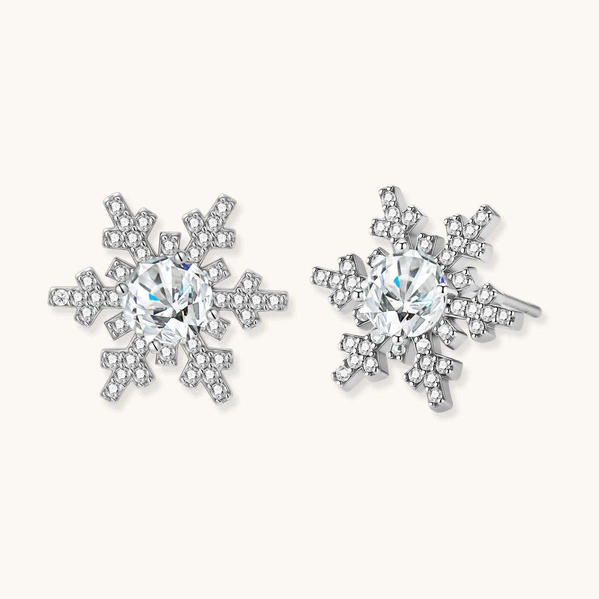 Sterling silver snowflake stud earrings with brilliant moissanite centers and intricate geometric patterns on cream background