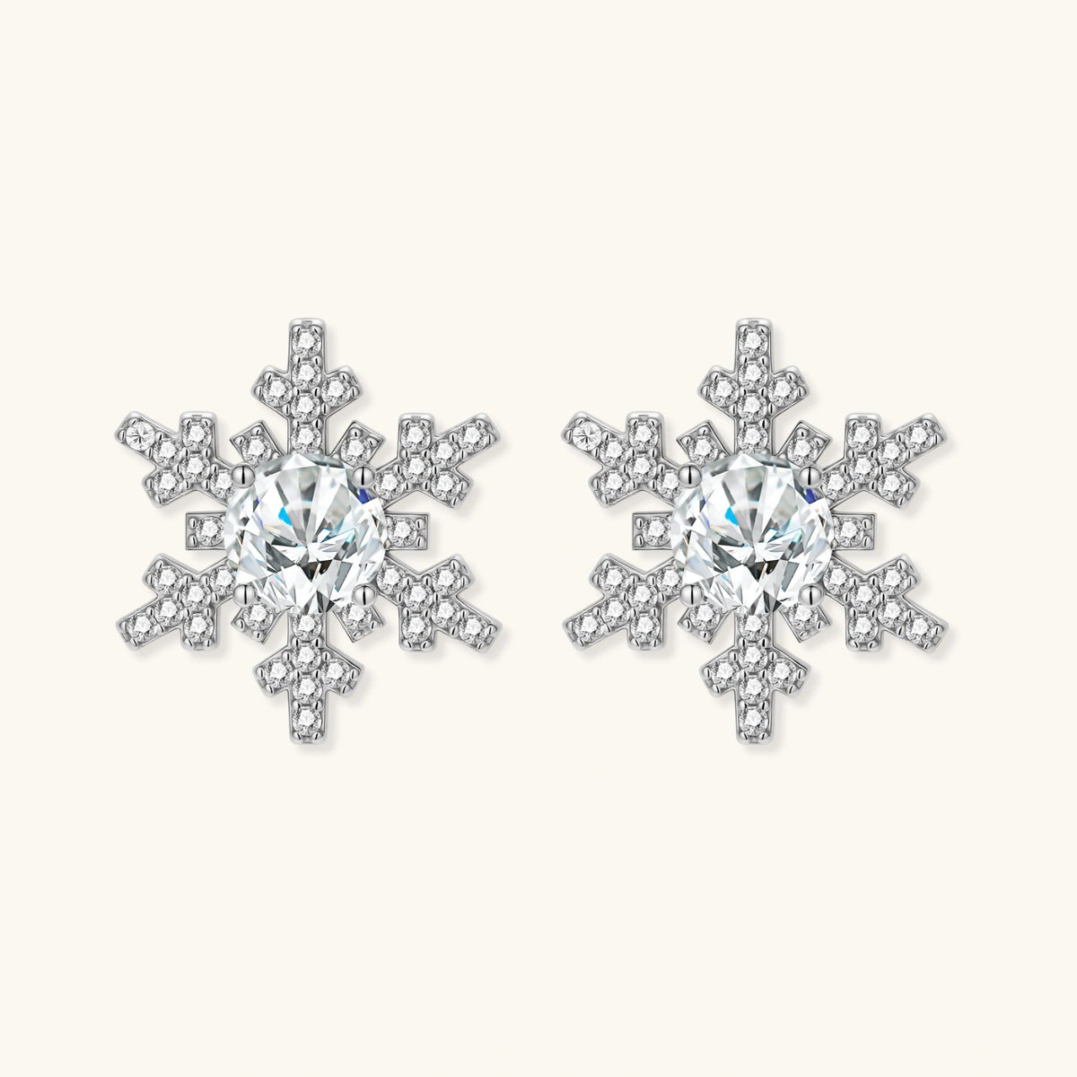 Sterling silver snowflake stud earrings with brilliant moissanite centers and intricate geometric patterns on cream background